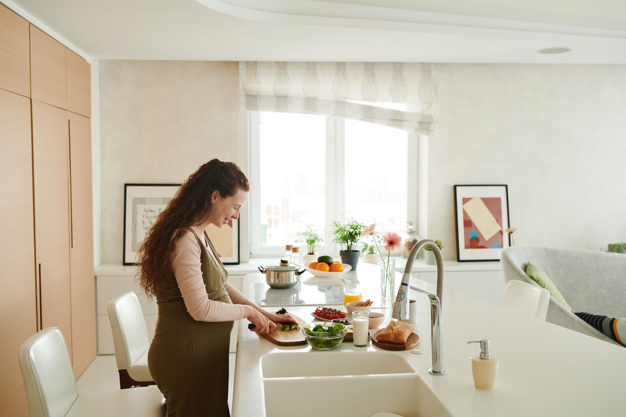 Femme enceinte coupe légumes cuisine lumineuse